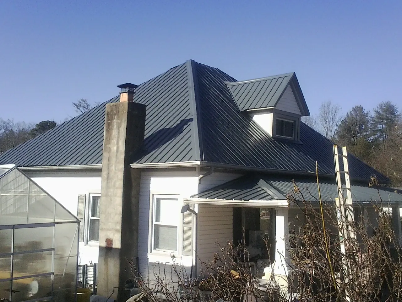 Dark blue standing seam metal roof on a white farmhouse with dormer — Slate & Tile Roof Repair by Roofing Brothers in Wabash