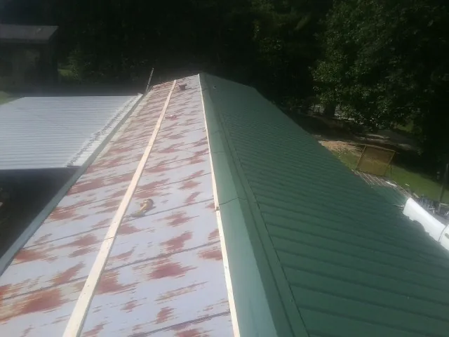 Old rusted panels beside newly installed green metal roofing — Wind Damage Roof Repair by Roofing Brothers in Wabash
