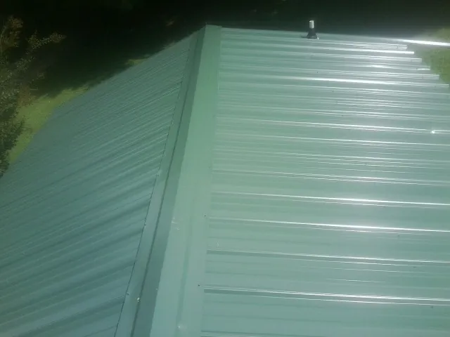 New green metal panels meeting at the ridge of a roof — Flat Roof Repair work by our crew in Wabash