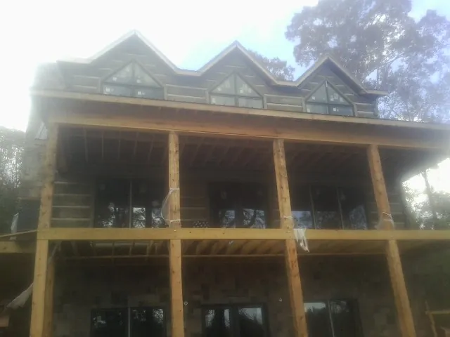 Dormers and porch framing on a large log home under construction — Roof Coating work by our crew in Wabash
