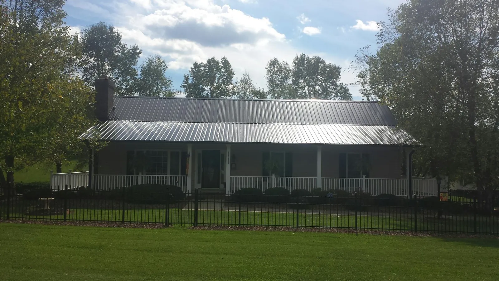 Gray metal roof on a brick ranch with a full width front porch — Gutter Guard Installation work by our crew in Wabash