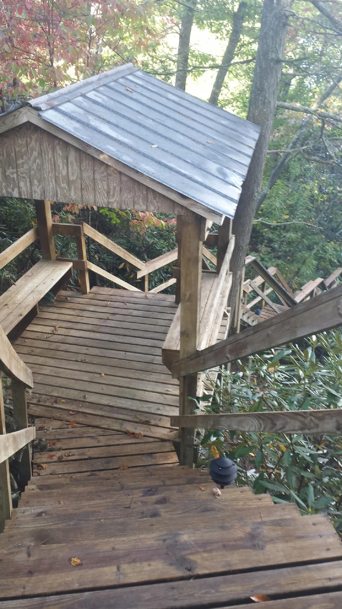 Metal roofed shelter over wooden steps on a wooded walkway — Skylight Repair & Installation work by our crew in Wabash