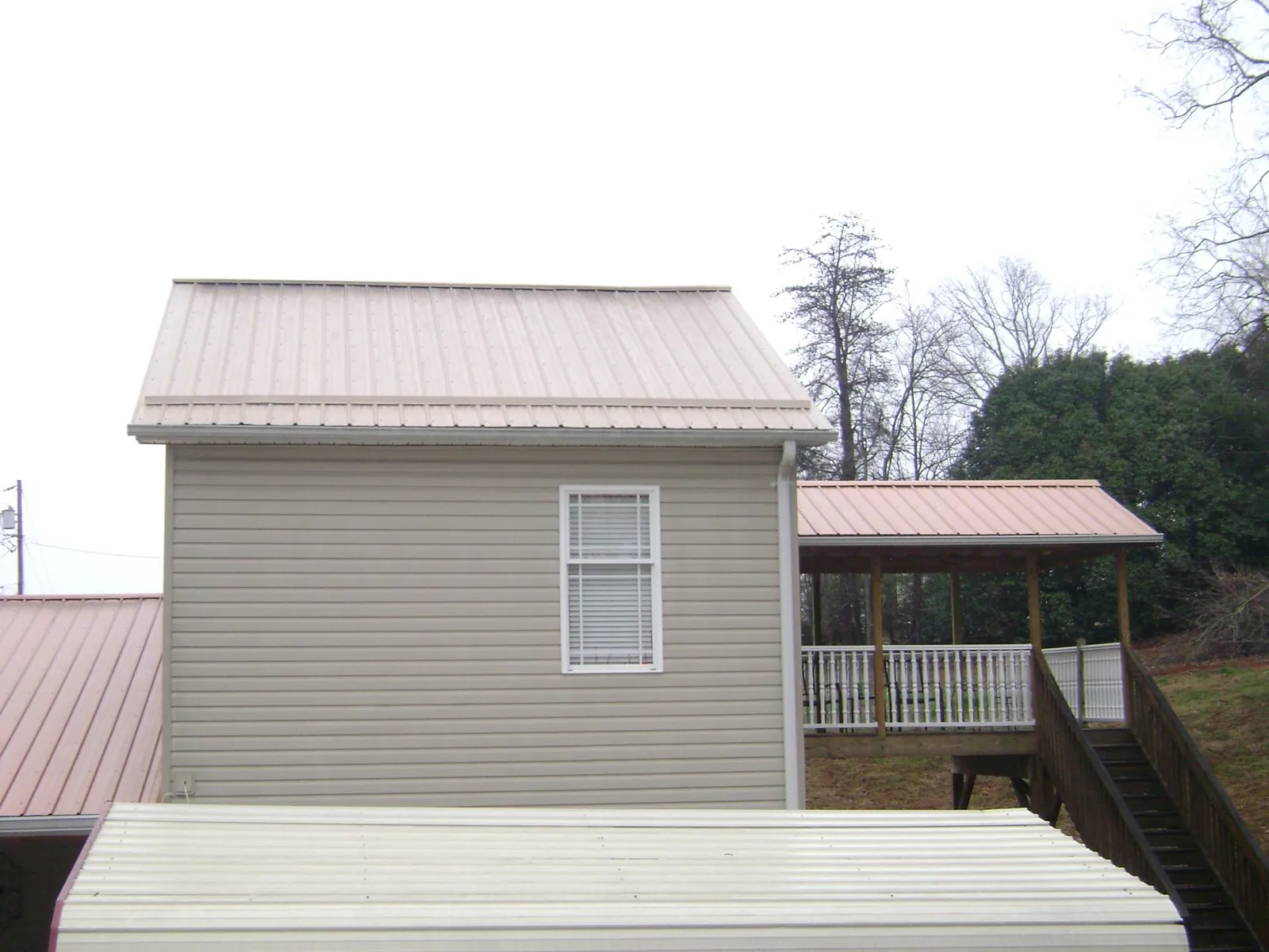 Tan metal roofs on a two story addition and attached porch, from a Roof Replacement job in Wabash