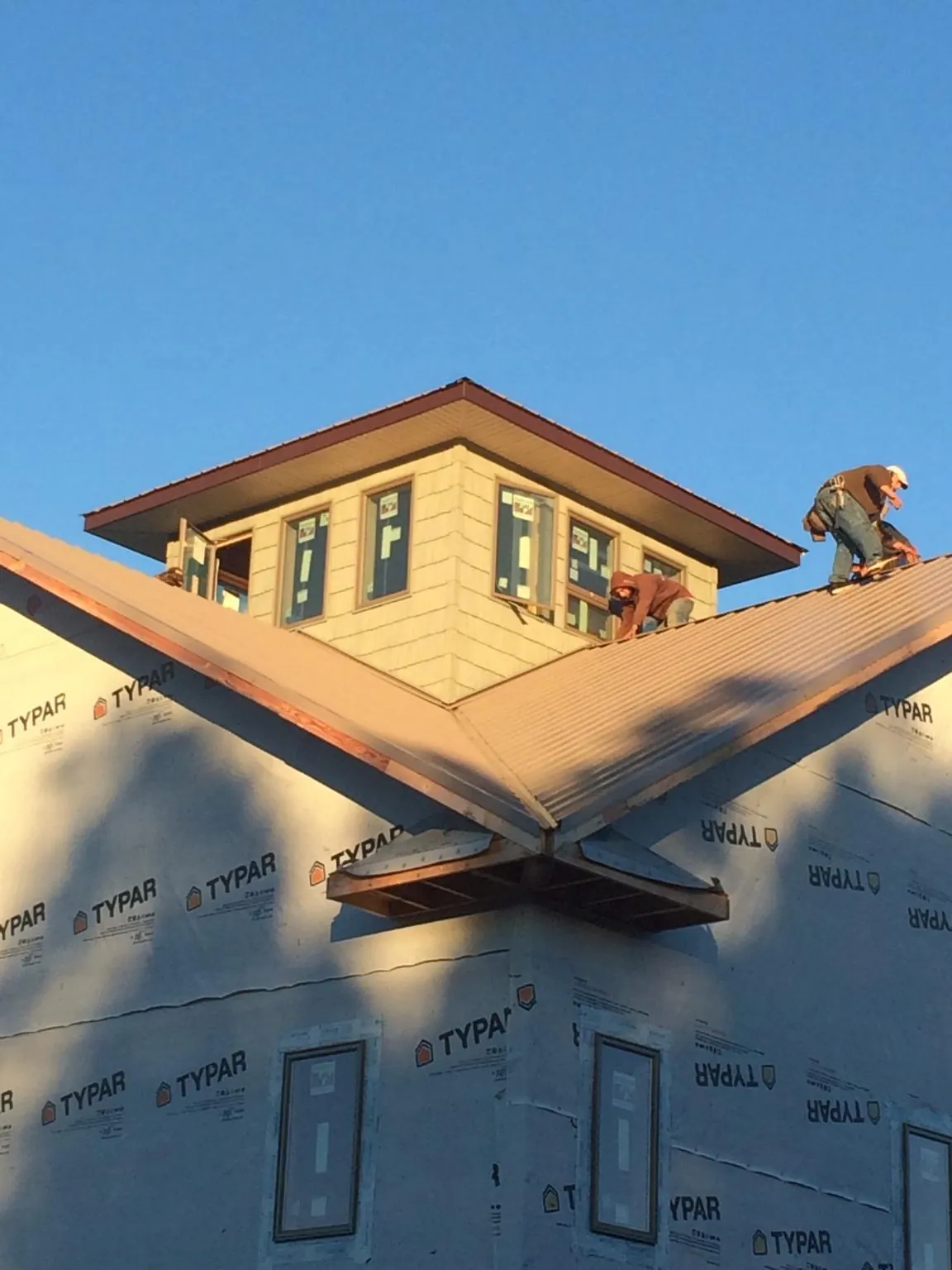 Roofers working around a rooftop cupola on a new metal roof at sunset — Roof Waterproofing in Wabash by Roofing Brothers